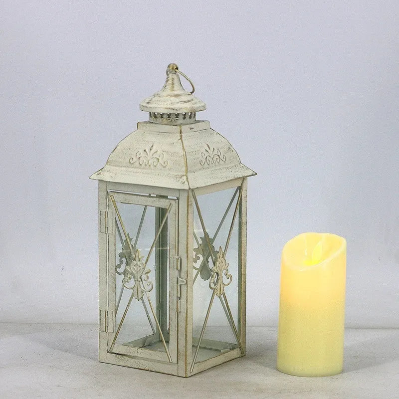 Black wrought iron floor-standing storm lantern with clear tempered glass panels on a garden patio.