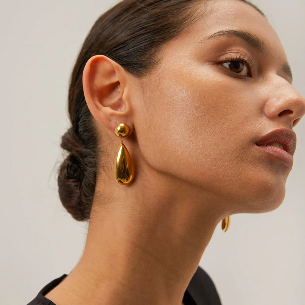 Gold stainless steel earrings with a geometric hemisphere and dangling water droplet pendant.