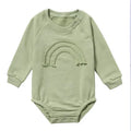 Baby wearing a beige waffle cotton long sleeve romper with rope ties, showing the triangle climbing style.