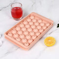 Blue silicone ice tray with lid producing 33 large round ice spheres on a kitchen counter