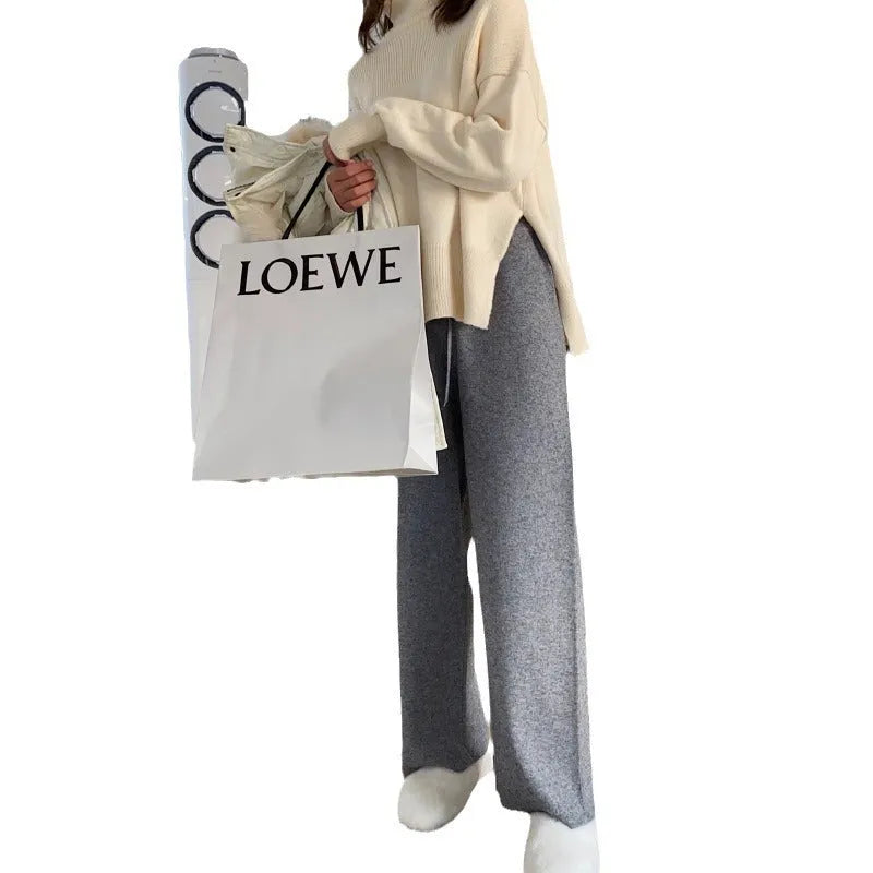 Woman wearing cream white knitted high-waist wide-leg winter trousers.