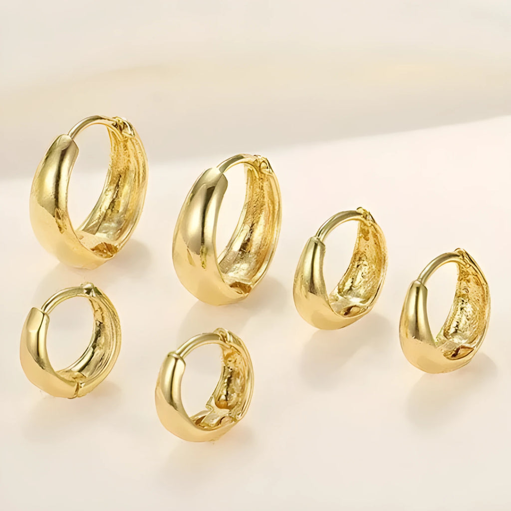 Three pairs of gold electroplated copper earrings with geometric ring design on a white background