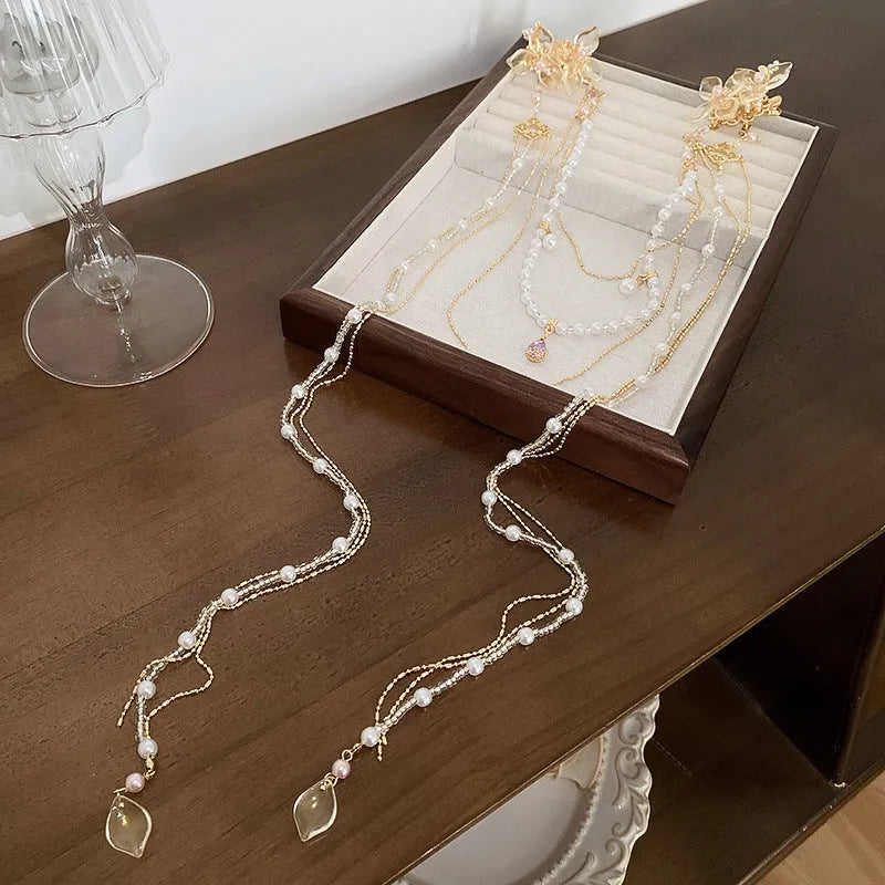 Women's decorative hairpin with pearl, diamond, and flower elements on long tassel with gold grip