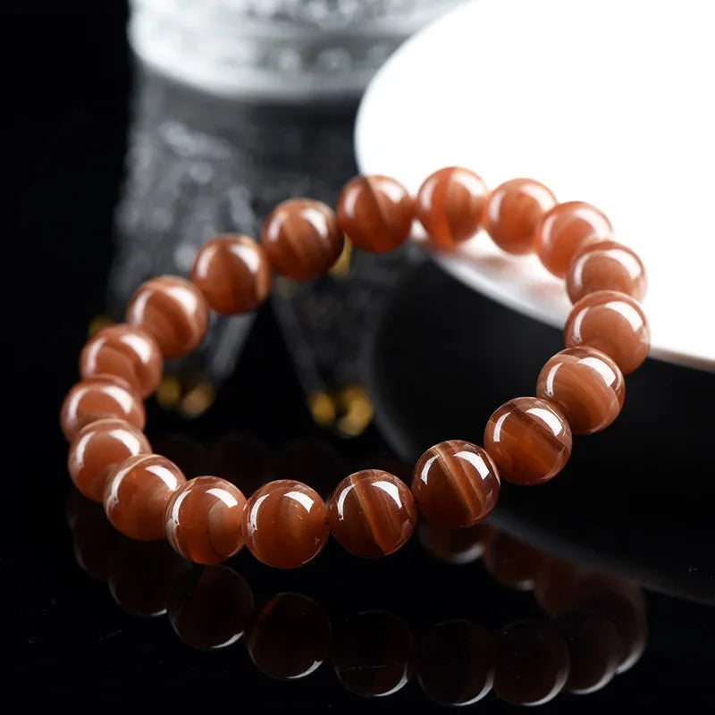 Natural Old Mine Rhodochrosite round bead bracelet with geometric design on wrist.