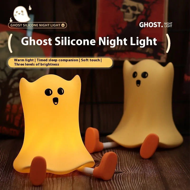 Ghost shaped silicone bedside lamp with touch control emitting soft yellow glow on a bedside table