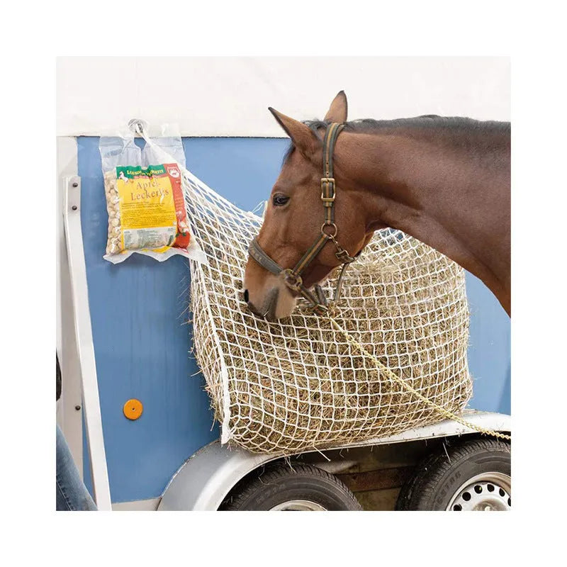 Woven polyethylene rope horse feeding bag in black hanging with hay visible through grid
