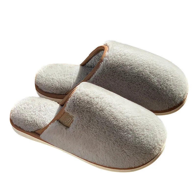Pair of solid-colour plush winter slippers with a slip-on design and a textured PVC sole.
