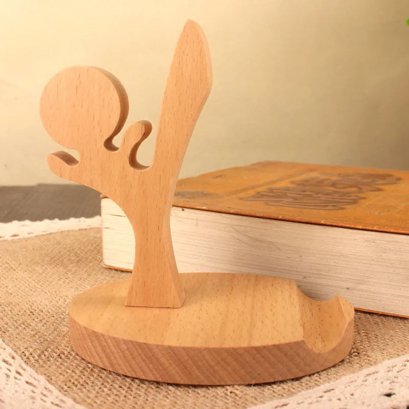 Sculpted beech wood lazy bracket phone holder with custom engraved text on a wooden desk.