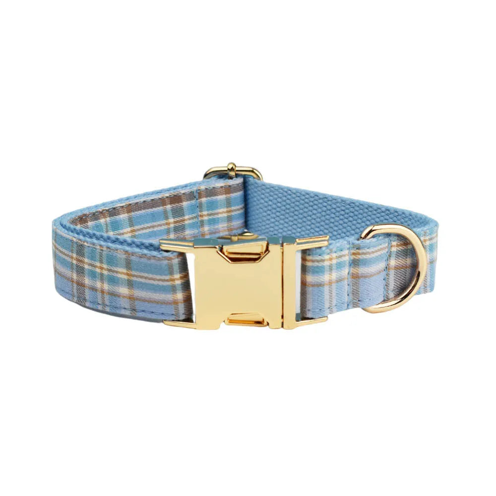 Sky blue grid pattern dog collar, leash, vest, and bow set laid out on a white background.
