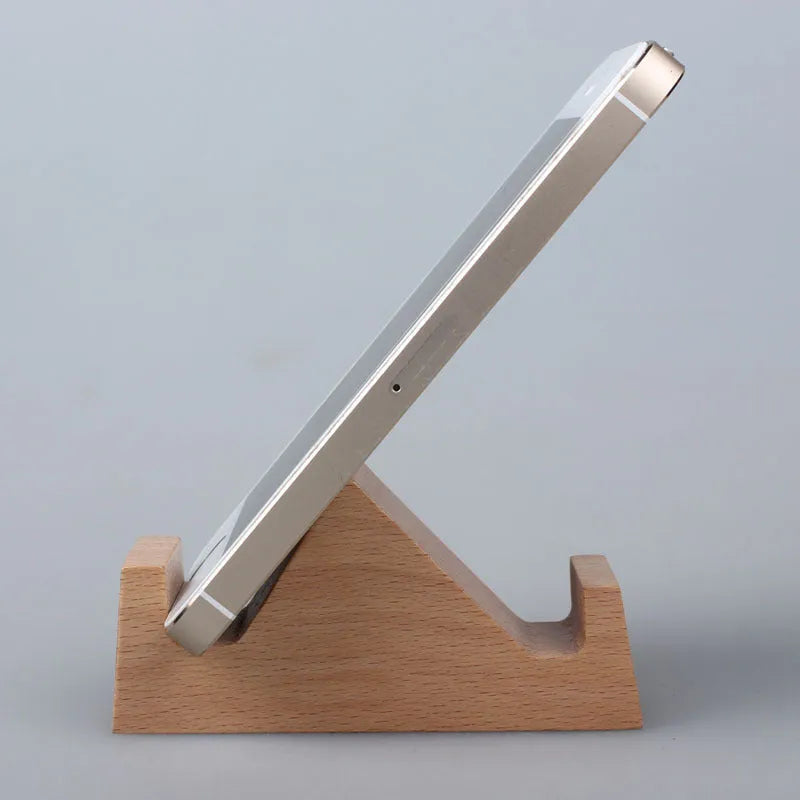 Sculpted beech wood lazy bracket phone holder with custom engraved text on a wooden desk.