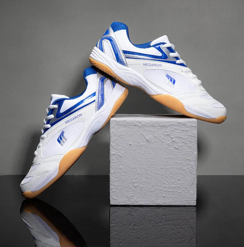 Table tennis training sneaker in white and blue with synthetic leather and mesh upper and lace-up front.