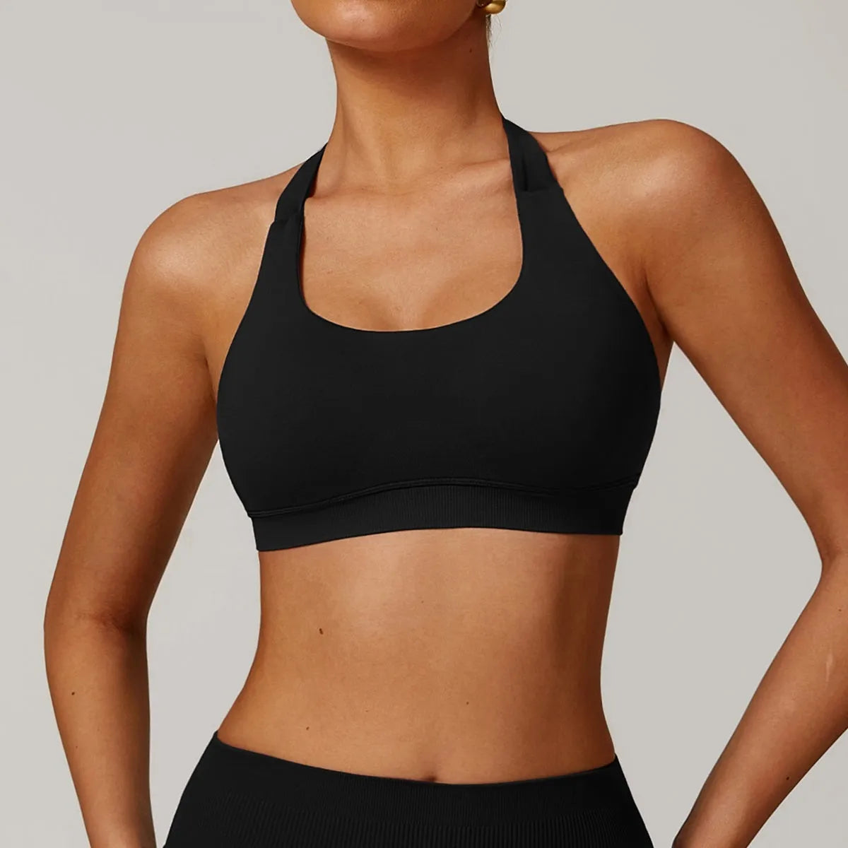 Close-up side view of a black halter neck sports bra for women, showing the strap detail and smooth nylon fabric.