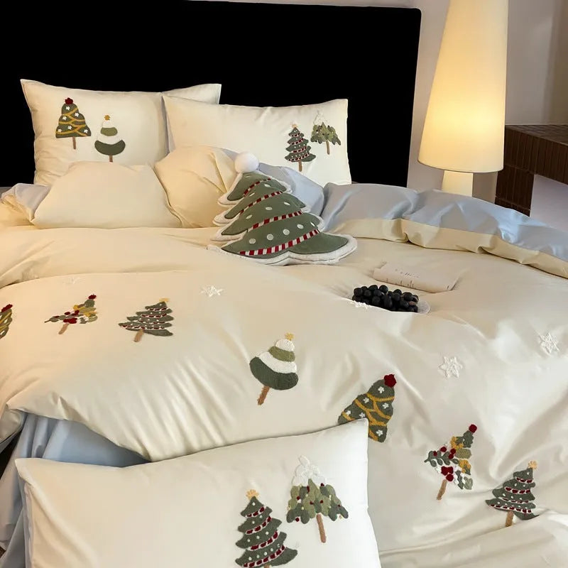 Cream blue cotton duvet cover with embroidered Christmas tree and floral design, laid on a bed with matching pillowcases.