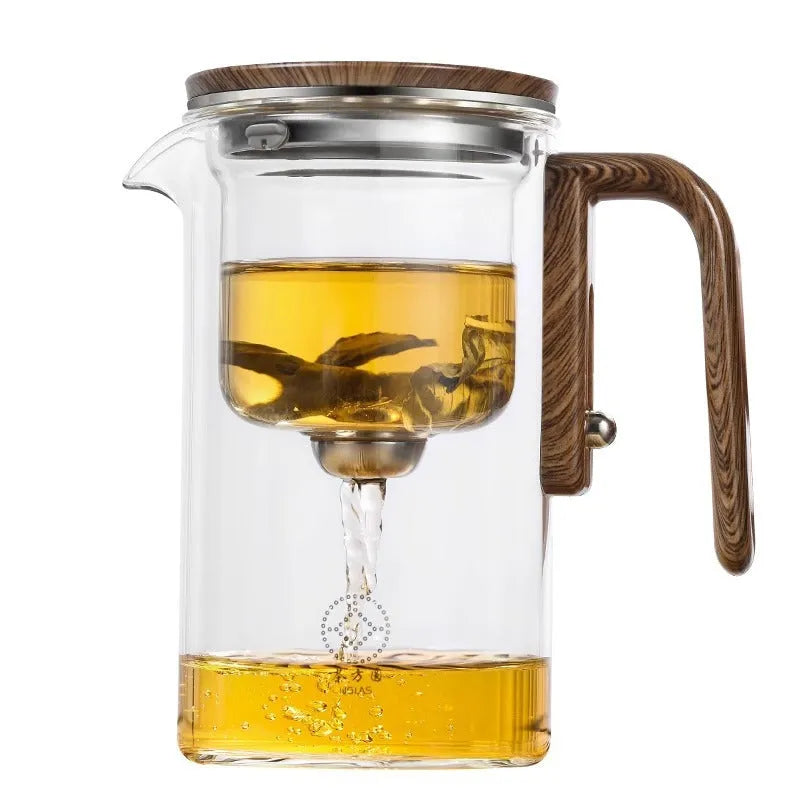 Glass teapot with wooden handle showing magnetic tea separation button and drip-free spout.