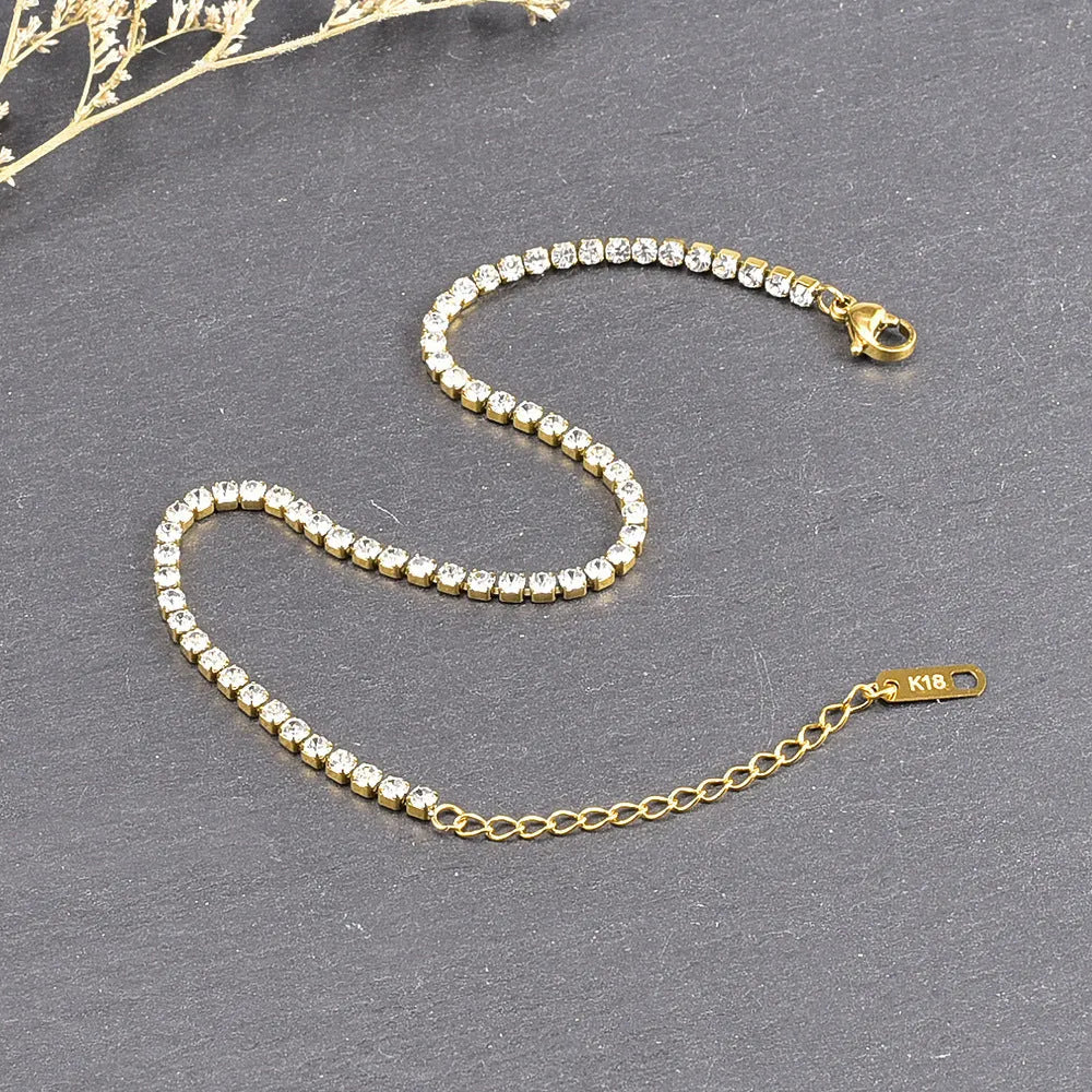 Gold titanium steel anklet with small fruit-shaped pendant and adjustable tail chain on bare ankle