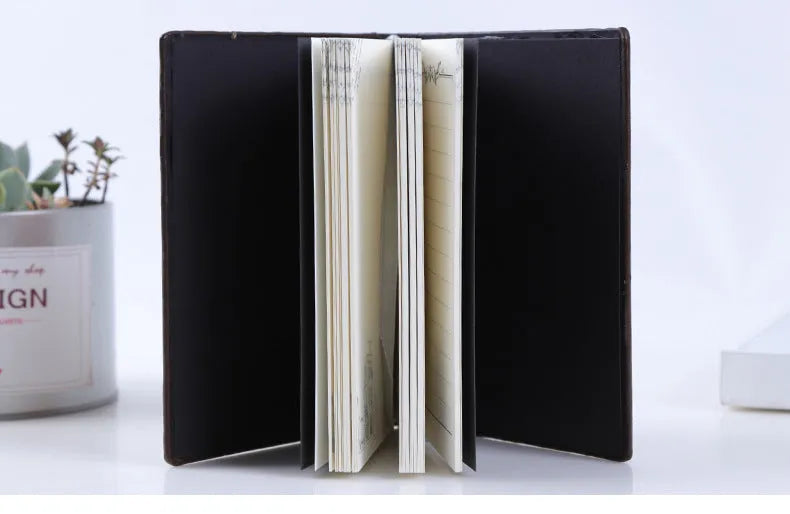 Hardcover PU leather notebook with embossed retro cover and brushed bronze details, open at 180 degrees showing beige pages