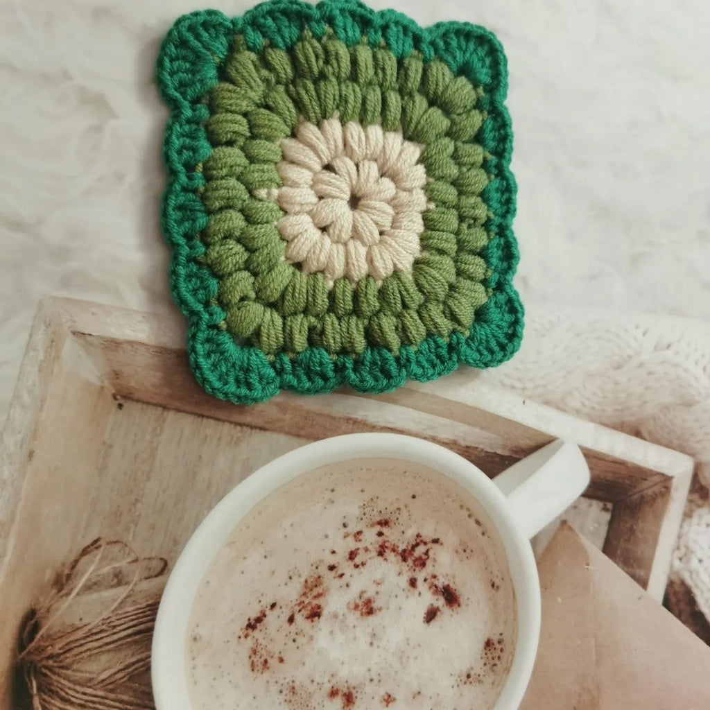 Square crocheted wool placemat with Grandmother Lattice pattern for cup heat protection.