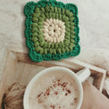 Square crocheted wool placemat with Grandmother Lattice pattern for cup heat protection.