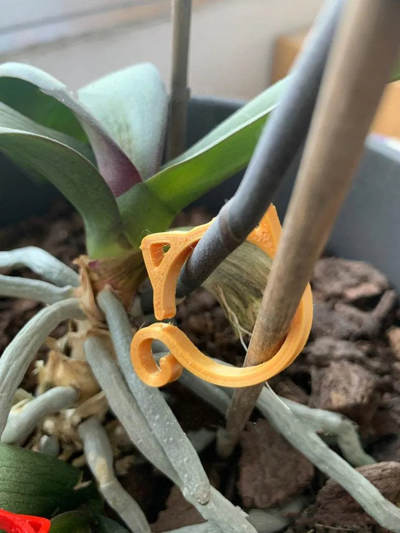 A colourful cat-shaped plastic clip for securing plant stems in the garden.