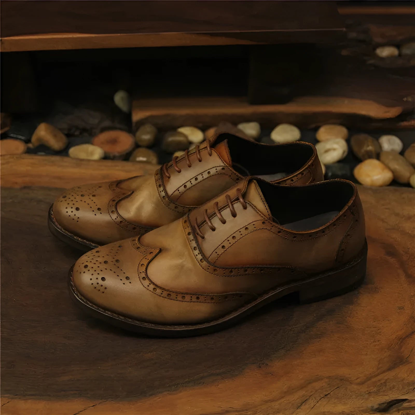 Light brown men's distressed leather lace-up shoes on a wooden surface, showing hand-carved details and round toe design.
