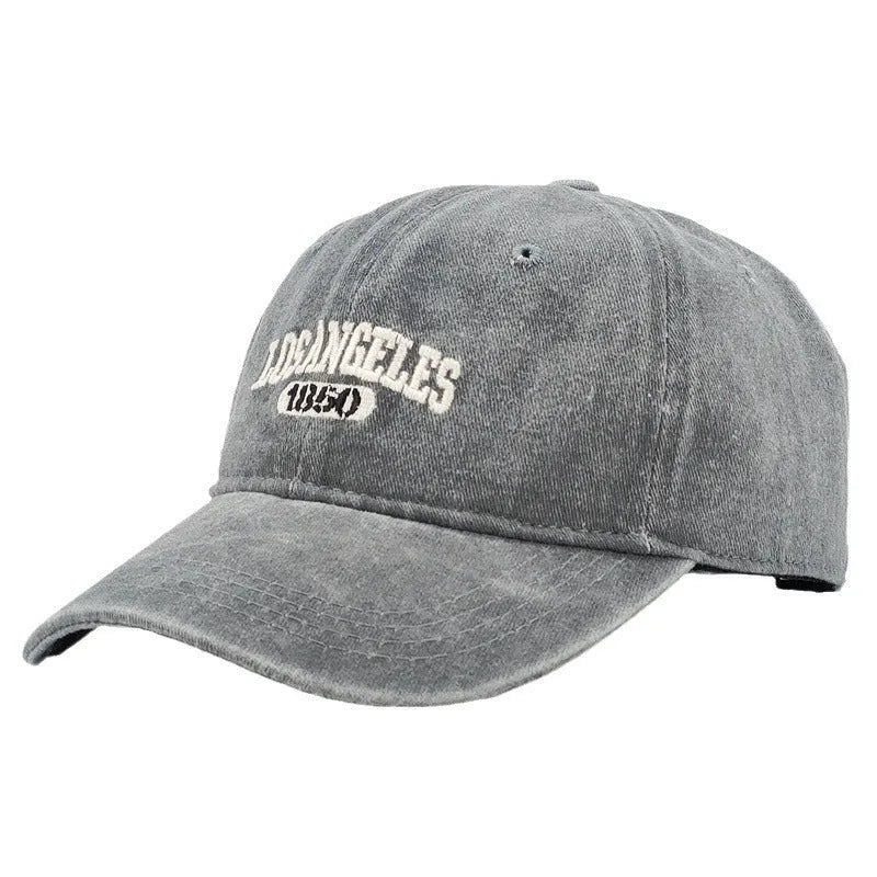 Retro beige peaked cap with embroidered letters, showing distressed fabric texture and adjustable strap.