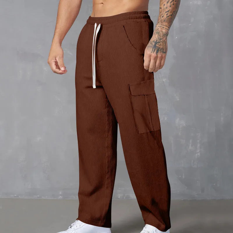 Man wearing navy blue loose-fit corduroy cargo trousers with a drawstring waist.