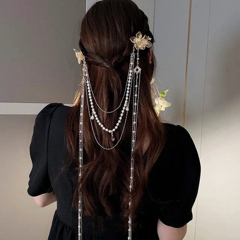 Women's decorative hairpin with pearl, diamond, and flower elements on long tassel with gold grip
