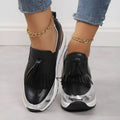Women's black casual platform shoes with a tassel detail and a distinctive muffin-style wedge heel.
