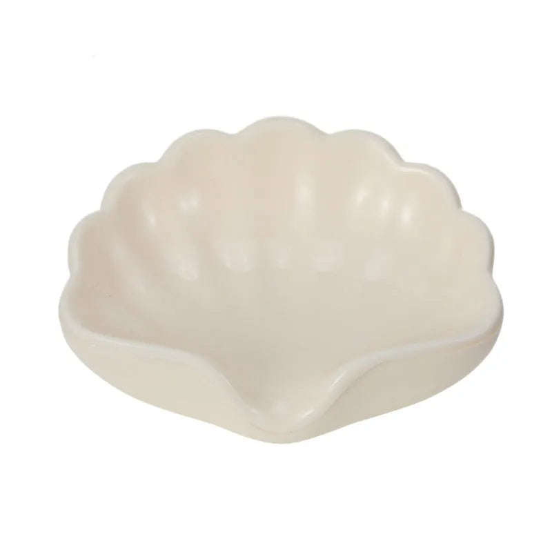 White or pink plastic shell-shaped soap dish for bathroom use on a counter.