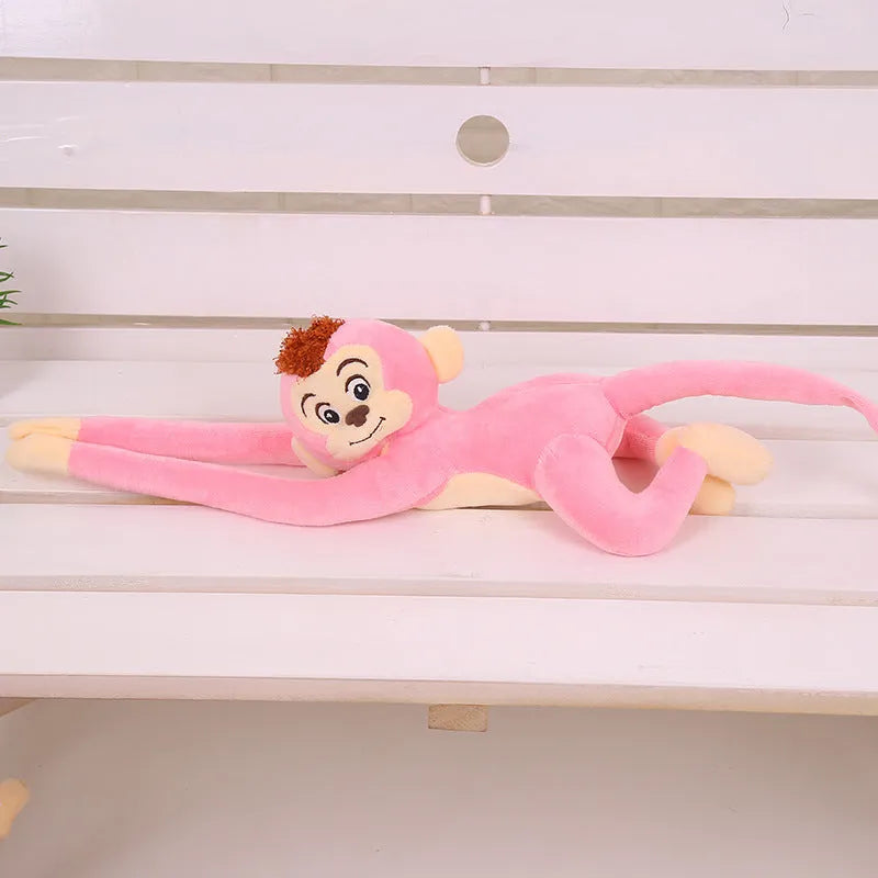 Long arm plush monkey toy hanging over a curtain pole in dark brown colour.