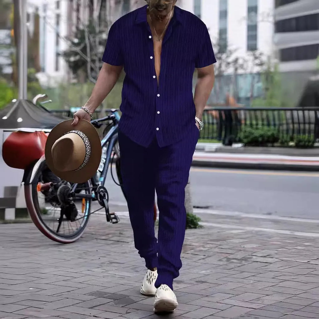 Man wearing a casual short-sleeve shirt and trousers beach suit set in a light blue colour.