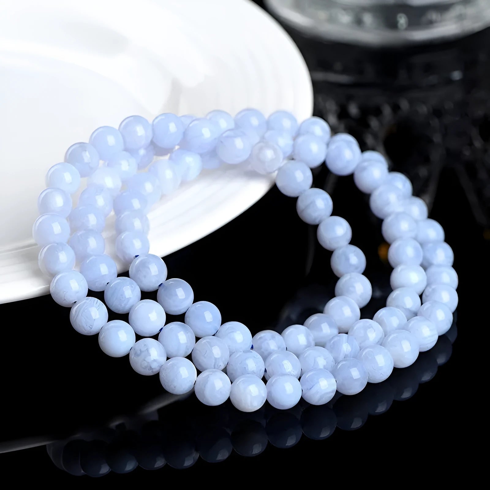 Blue agate bracelet with striped beads and a Ruyi charm on a wrist.