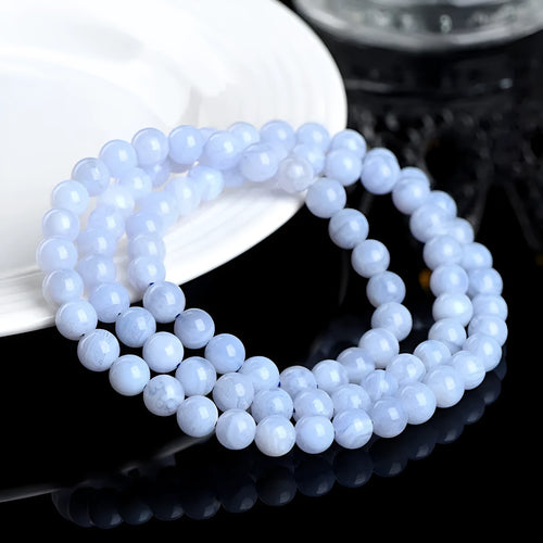 Blue agate bracelet with striped beads and a Ruyi charm on a wrist.