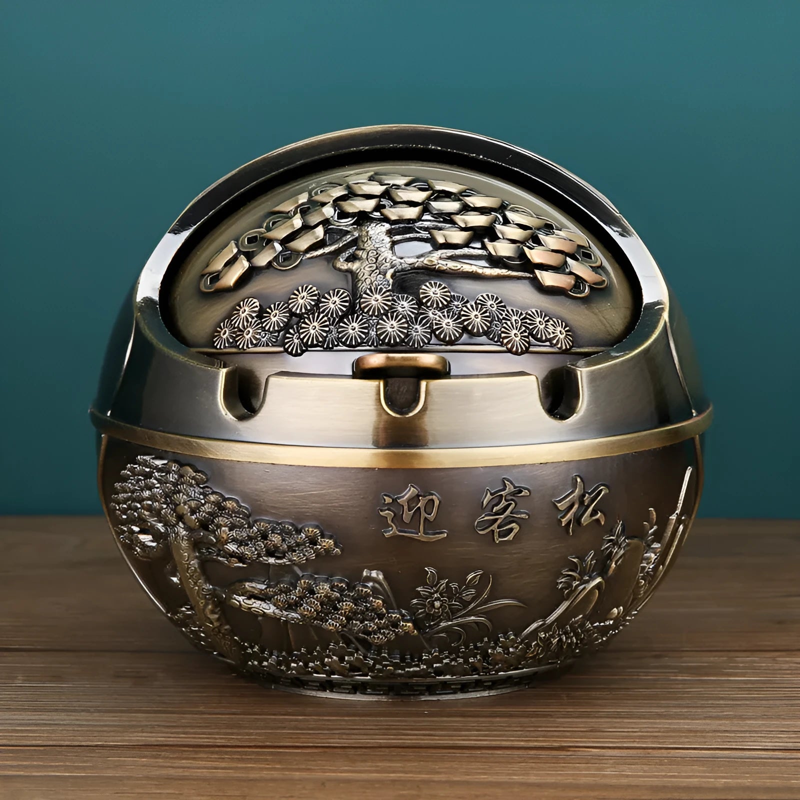 Bronze and red copper alloy decorative ashtray with smoke-extinguishing slot on a table.