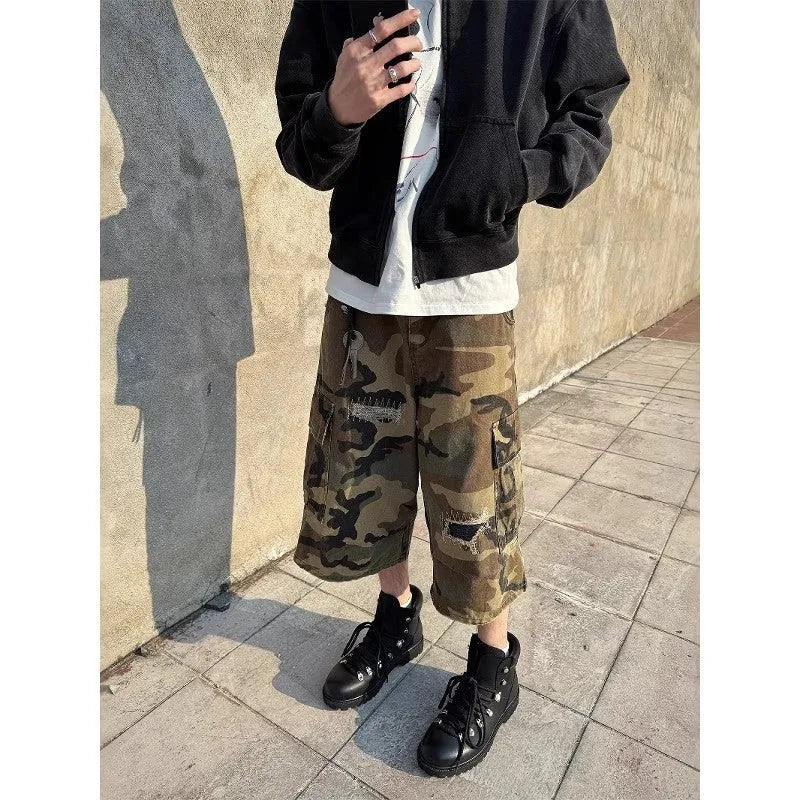 Men's loose-fit camouflage cropped jeans with ripped details and patches on a straight leg.