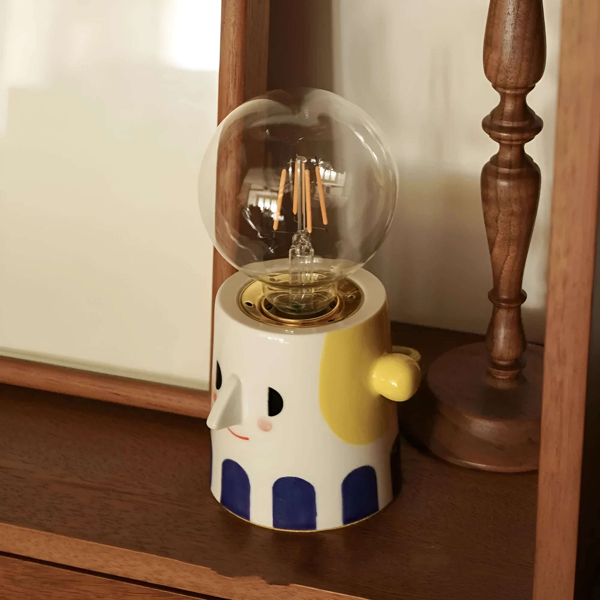Handmade ceramic bedside lamp with white ball headlight shade on a wooden table.
