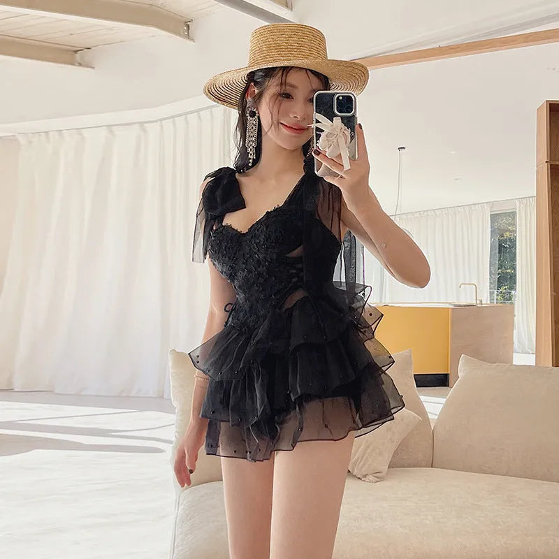 Black one-piece swimsuit with gathered chest detail on a model, showing conservative cut.