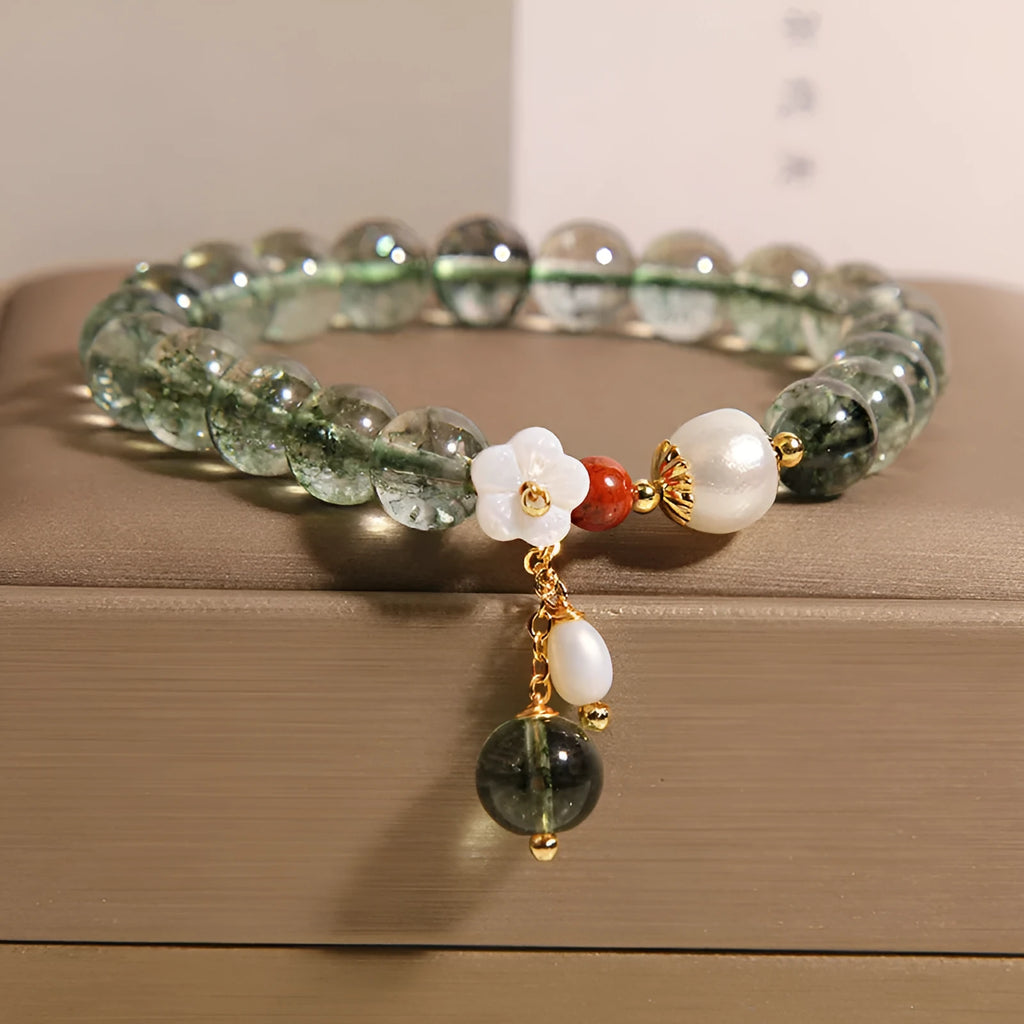 Women's green phantom quartz crystal bracelet with small shell flower accent on wrist.
