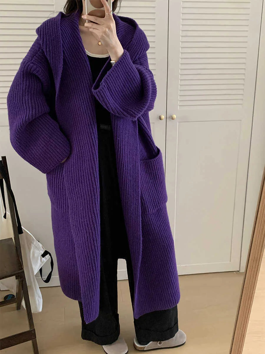 A woman wearing a long, loose, milky white hooded cardigan coat with raglan sleeves.