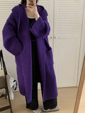 A woman wearing a long, loose, milky white hooded cardigan coat with raglan sleeves.