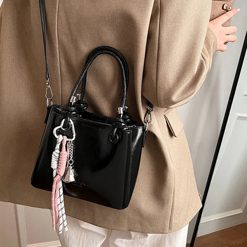 Women's PU one-shoulder bucket messenger bag in black with pendant, showing front view with single strap