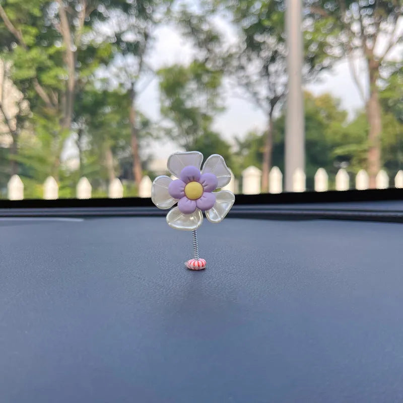 Small colourful plastic swing car decoration hanging from a rear-view mirror, showing blue, green, pink, purple, and yellow colour options.
