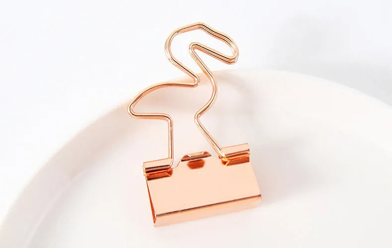 Gold metal long tail clip with a decorative bow charm on a white background.