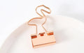 Gold metal long tail clip with a decorative bow charm on a white background.