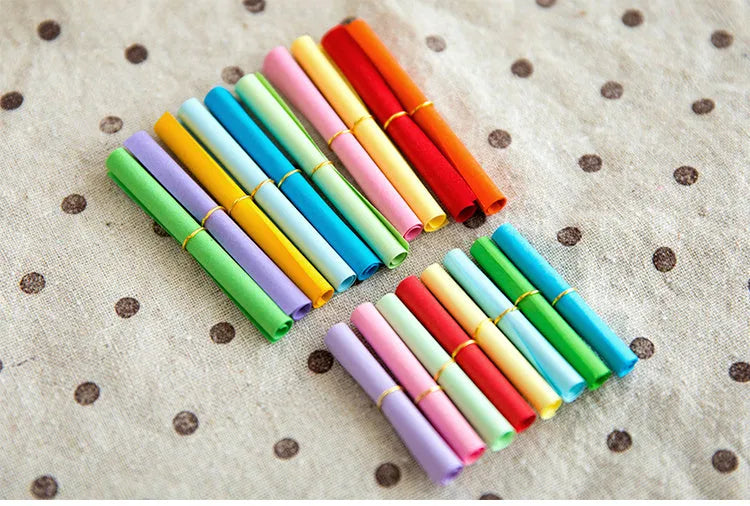 Colourful miniature paper scrolls for drift bottle messages with central eyelet for string attachment