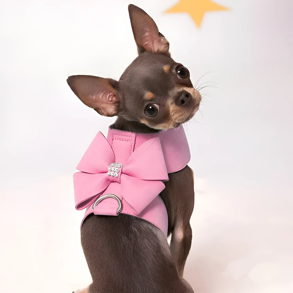 A pink dog harness with a white bow knot on an adjustable microfiber chest strap.