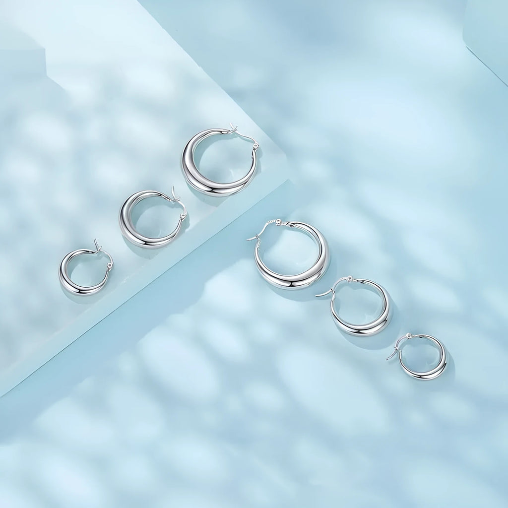A pair of copper geometric ring ear clips with a silver needle, shown in large, medium, and small sizes.