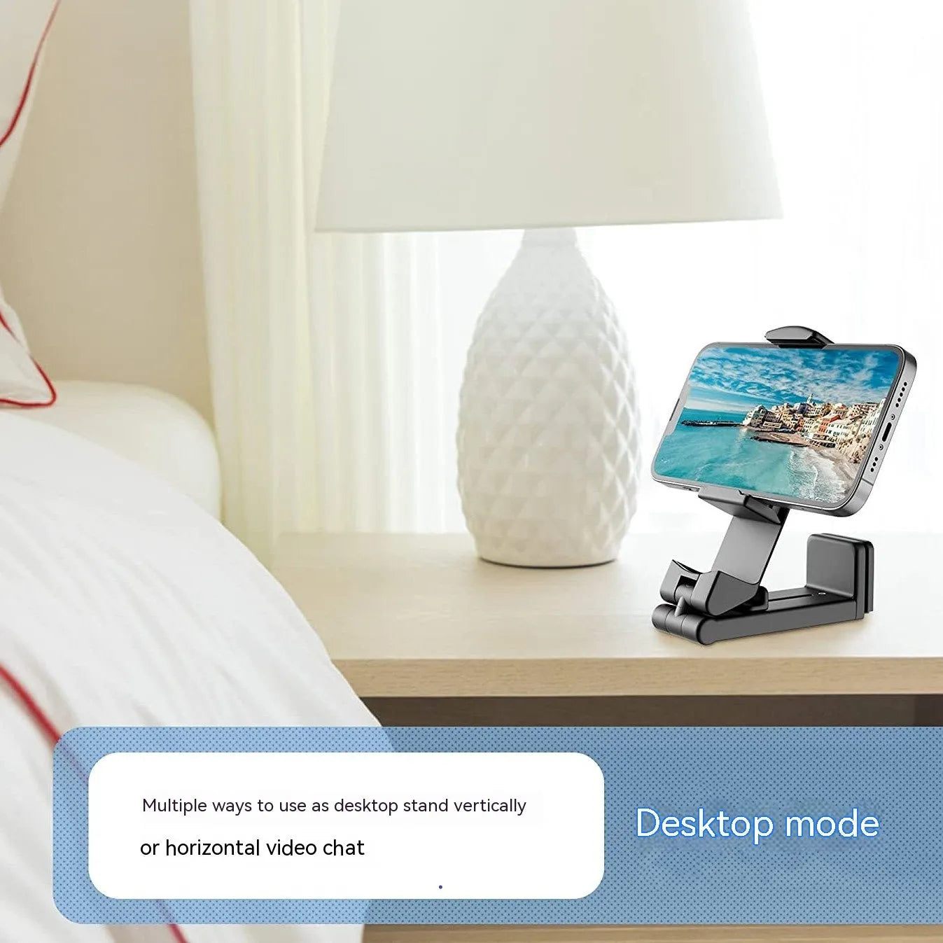 A black foldable phone holder with a rotating base, shown holding a mobile phone in landscape orientation.