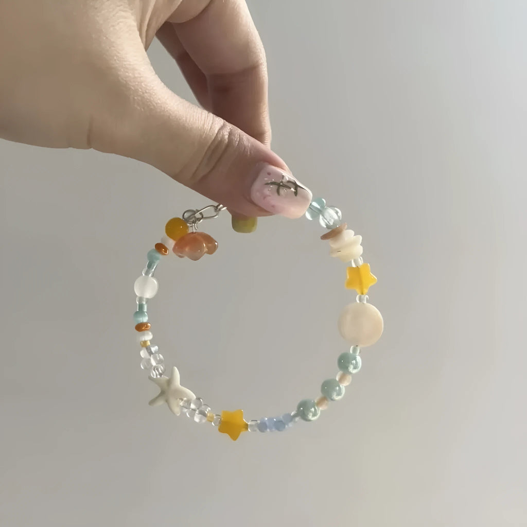 Orange mixed material women's bracelet with diamond shape and round decorative seaside elements.