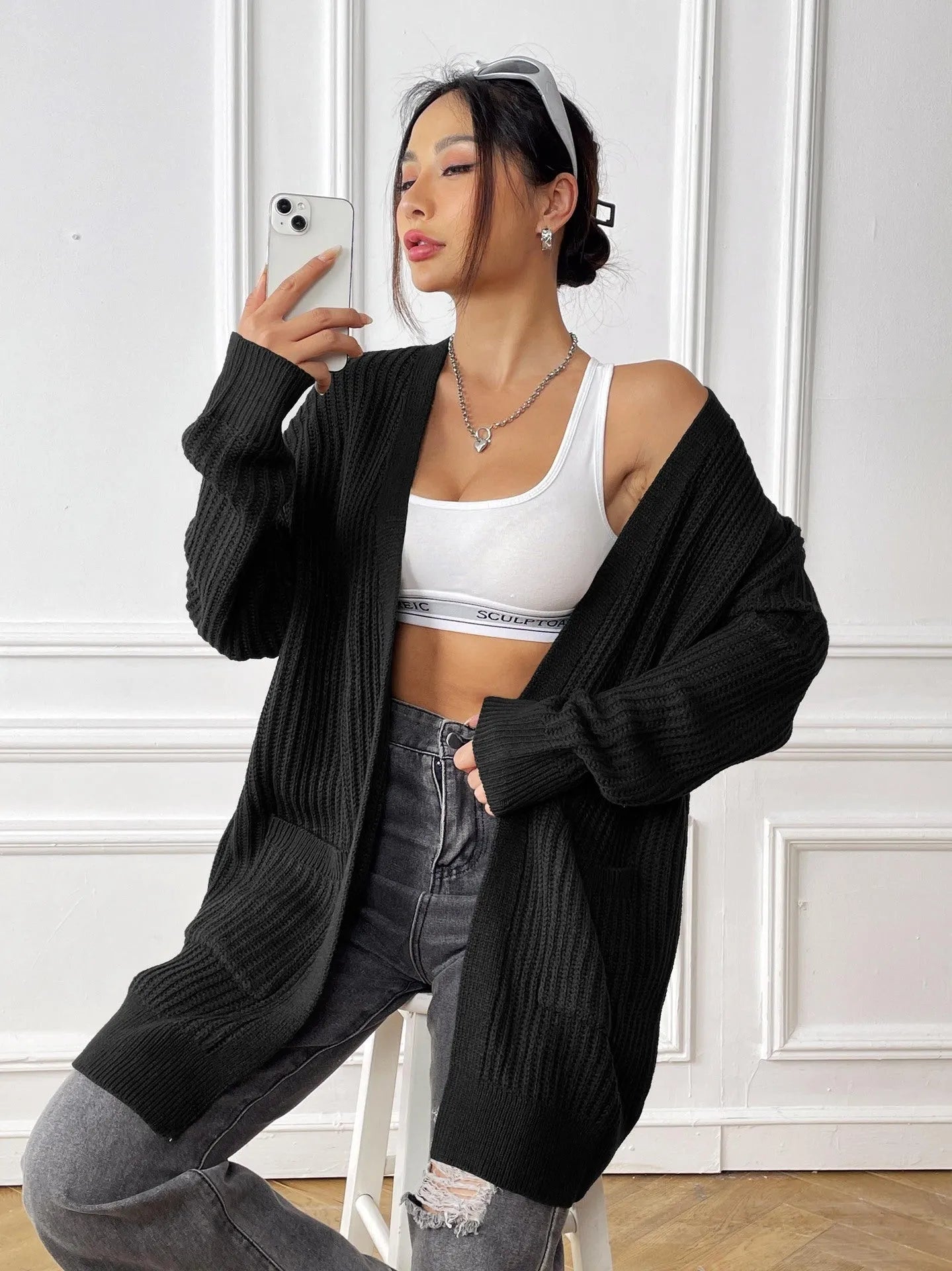 A dark green loose-fit women's cardigan sweater with two front pockets and long sleeves.